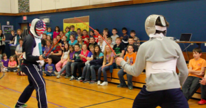 Tim Morehouse and Jeff Spear duel in front of students in Maine during their Fencing In The Schools assembly. Courtesy of Holly Buechel